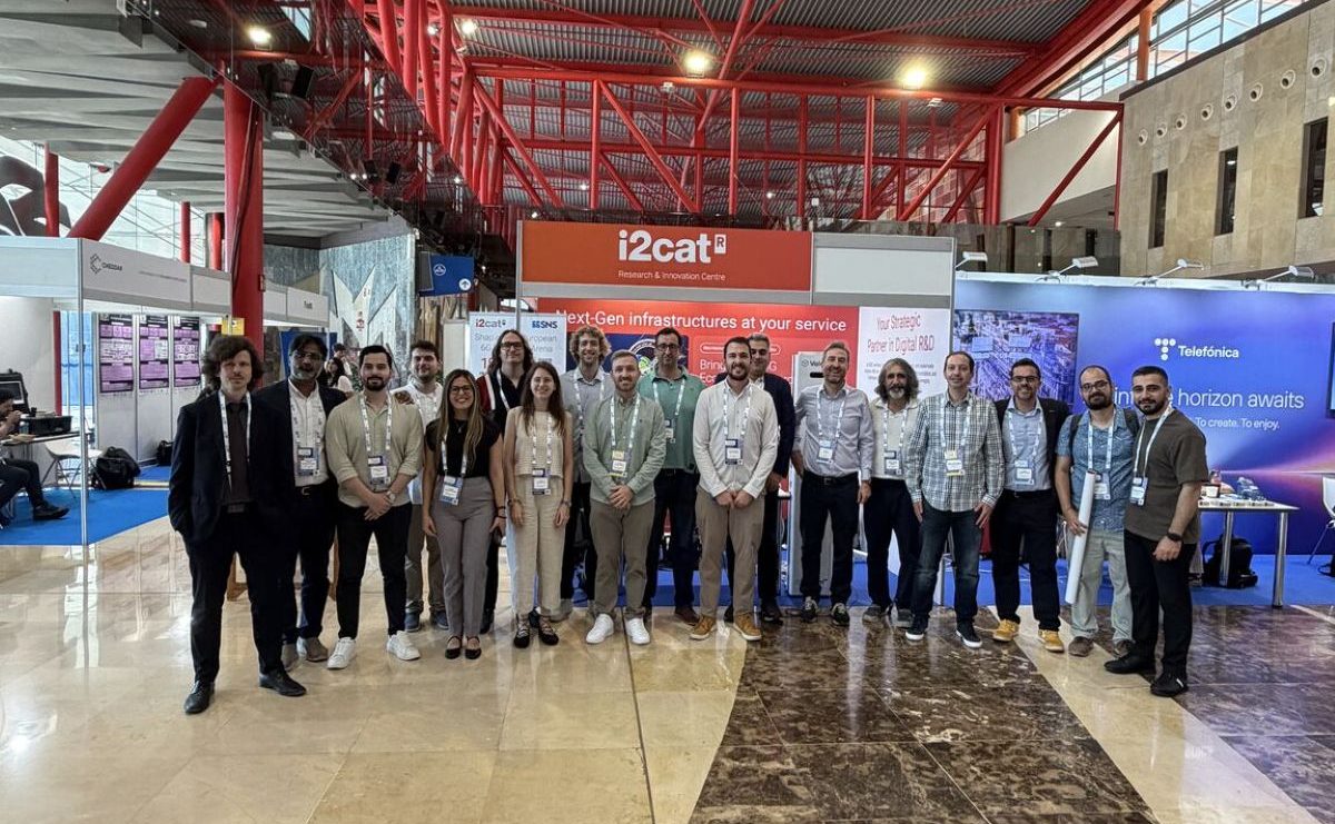 Group photo of professionals and researchers in an exhibition hall in front of the i2CAT Research & Innovation Centre booth